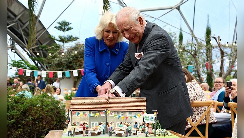 K&ouml;nigin Camilla und K&ouml;nig Charles k&auml;mpfen sich mit einem Schwert durch eine Torte.
