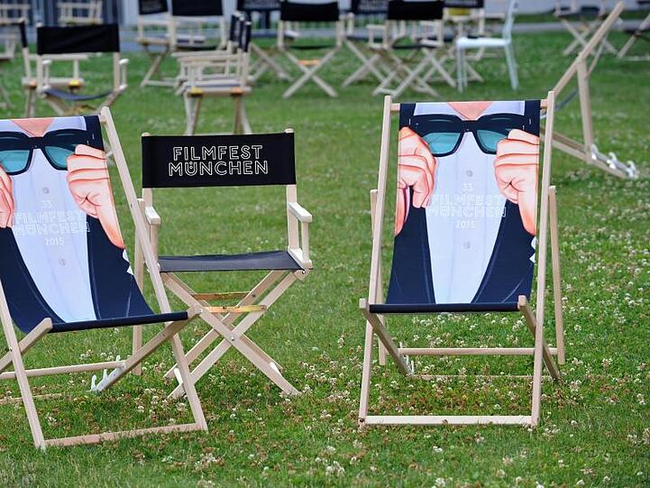 Liegestühle bedruckt mit dem Schriftzug "Filmfest München" stehen im Hof der Filmhochschule auf einer Wiese. Foto: Ursula Düren