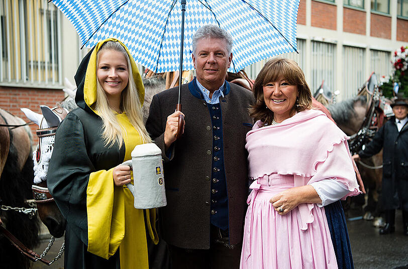 Dieter Reiter blickt beim Einzug der Festwirte gemeinsam mit seiner Frau Petra (r) und Viktoria Ostler, dem Münchner Kindl, in die Kamera.