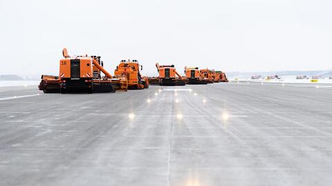 Zahlreiche versetzt fahrende Räumfahrzeuge mit Schneeschaufeln befreien die Startbahn am Flughafen vom Schnee. Foto: Matthias Balk/Archiv