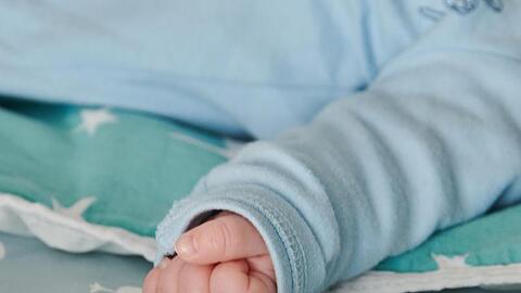 Die Hand eins Babys ist zu einer kleinen Faust geballt.
