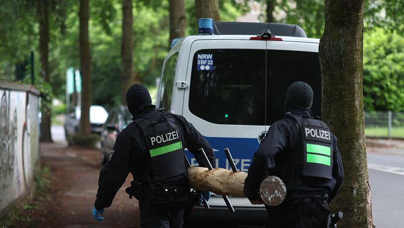 Polizisten tragen einen Rammbock.