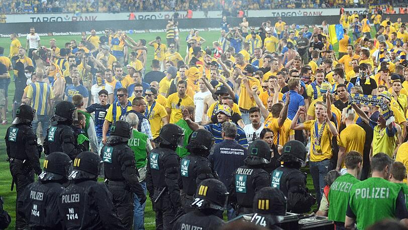 Braunschweiger Fans stehen Polizisten und Ordnern nach dem Abpfiff auf dem Platz gegenüber. Braunschweiger Fans stehen Polizisten und Ordnern nach dem Abpfiff auf dem Platz gegenüber.