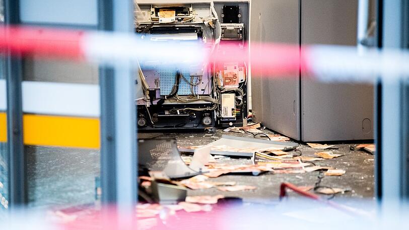 Geldscheine und verbogene Metallteile liegen am Boden einer Bankfiliale, in der am frühen Morgen ein Geldautomat gesprengt wurde.