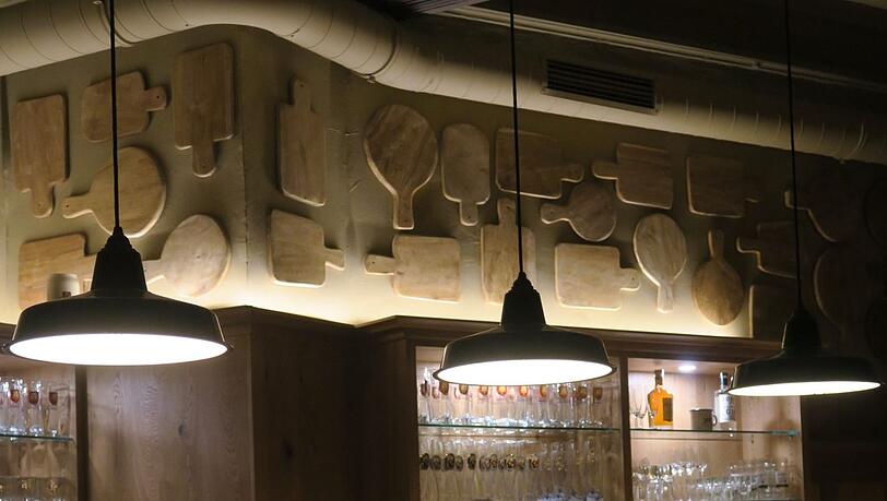 Besondere Deko über der Bar: zig Brotzeitbrettl aus Holz.