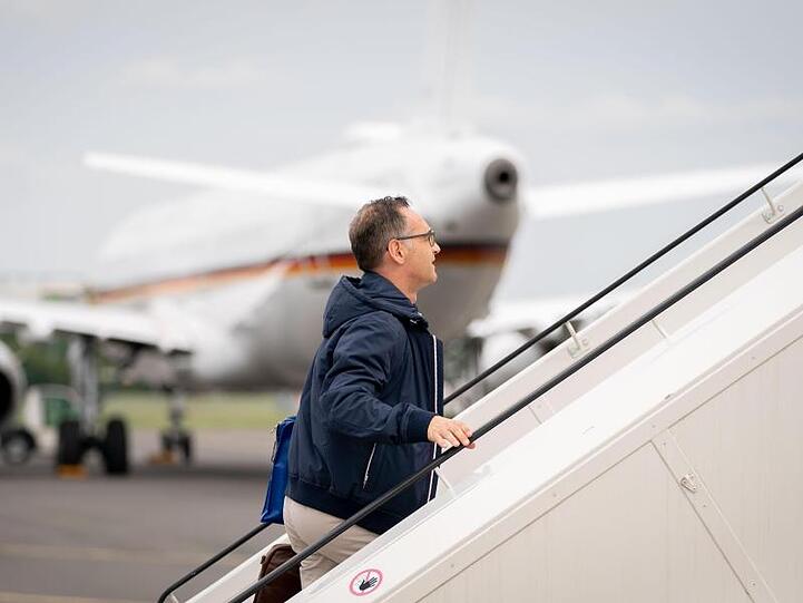 Außenminister Heiko Maas geht die Gangway zum Airbus A319 der Luftwaffe auf dem militärischen Teil des Flughafens Tegel hinauf. Im Hintergrund steht ein defekter Airbus A321 der Luftwaffe, der eigentlich für die Reise vorgesehen war.
