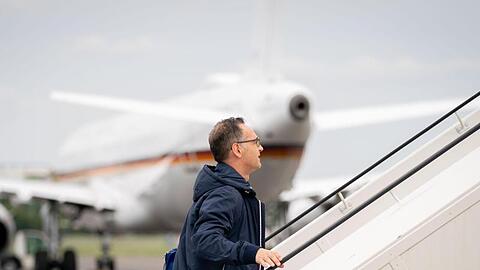 Außenminister Heiko Maas geht die Gangway zum Airbus A319 der Luftwaffe auf dem militärischen Teil des Flughafens Tegel hinauf. Im Hintergrund steht ein defekter Airbus A321 der Luftwaffe, der eigentlich für die Reise vorgesehen war.