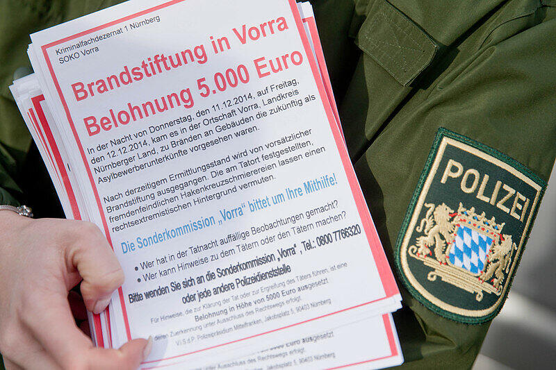 Eine Polizistin hält am 13.12.2014 in Vorra (Bayern) Fahndungszettel zum Brandanschlag in der Gemeinde in den Händen. Die Polizei sucht fieberhaft nach den Verbrechern.