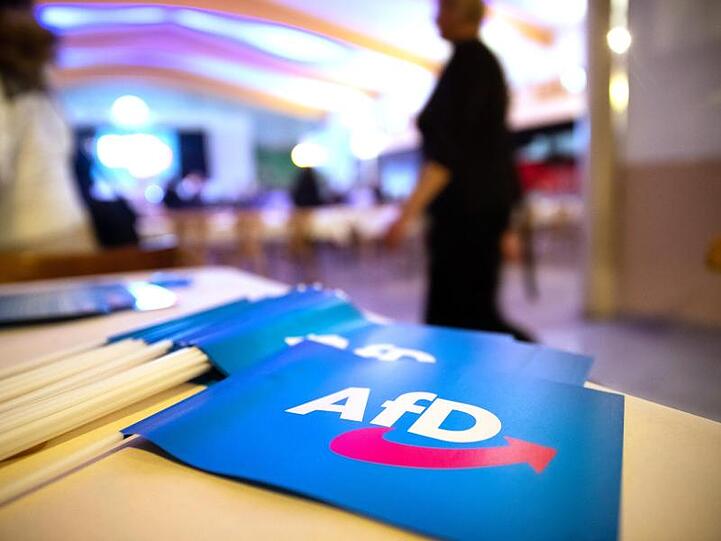 Fähnchen mit dem Logo der AfD liegen beim Landesparteitag der AfD Bayern auf einem Tisch. Foto: Daniel Karmann