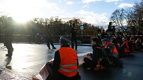 Klimaaktivisten der Umweltschutzbewegung "Letzte Generation" sitzen auf einer Straße.