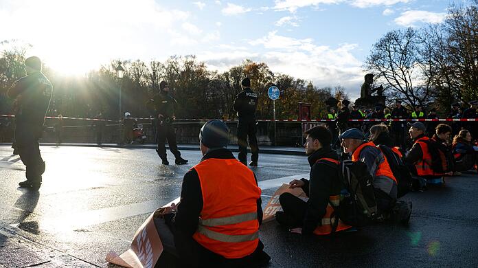 Klimaaktivisten der Umweltschutzbewegung "Letzte Generation" sitzen auf einer Straße.