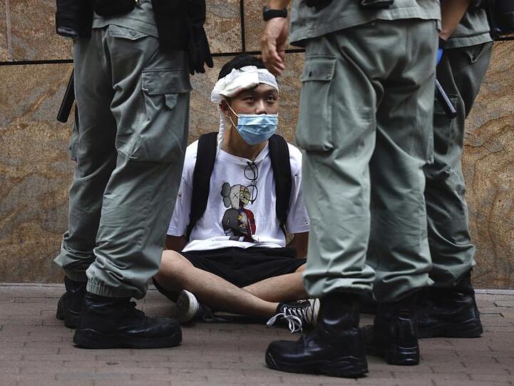 Bereitschaftspolizisten stehen im Hongkonger Central District um einen auf dem Boden sitzenden Demonstranten.