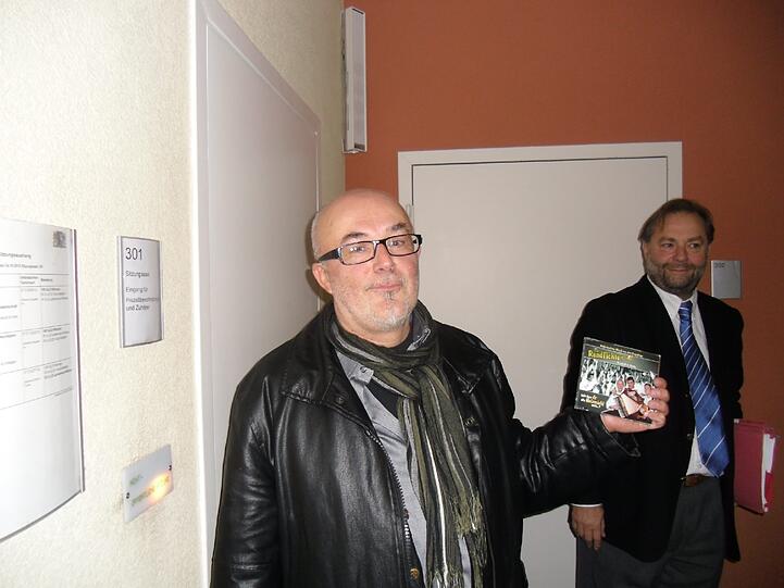 &bdquo;Holzmichl&ldquo;-Produzent Hermann Weindorf mit der Single vor dem Münchner Gerichtssaal, dahinter sein Anwalt Ralf Behrenz.