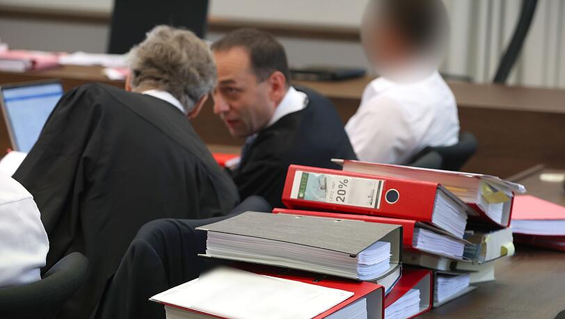 Akten liegen zwischen einem Landwirt (l) und seinem Anwalt im Landgericht auf der Anklagebank.