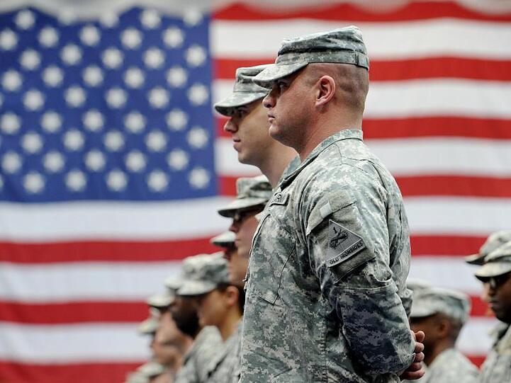 US-Soldaten stehen vor einer US-Flagge. Foto: Frank May/dpa/Archivbild