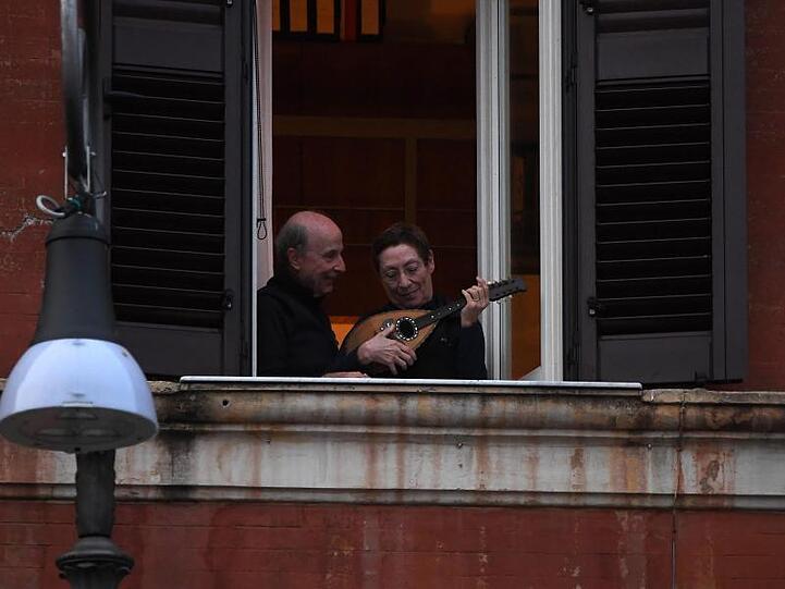Ein Mann und eine Frau mit einem Instrument an einem geöffneten Fenster in Rom.
