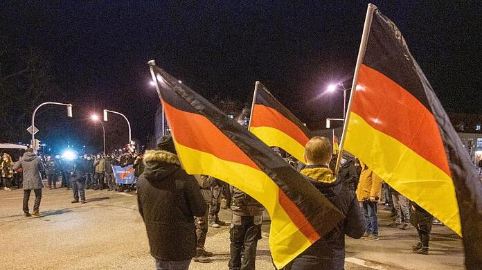 Teilnehmer einer Demonstration gegen die Corona-Maßnahmen tragen Deutschland-Fahnen.
