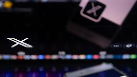 Auf dem offiziellen Profil der Plattform X auf dem Bildschirm eines Smartphones und auf dem Display eines Laptops ist der weiße Buchstabe X auf schwarzem Hintergrund zu sehen.