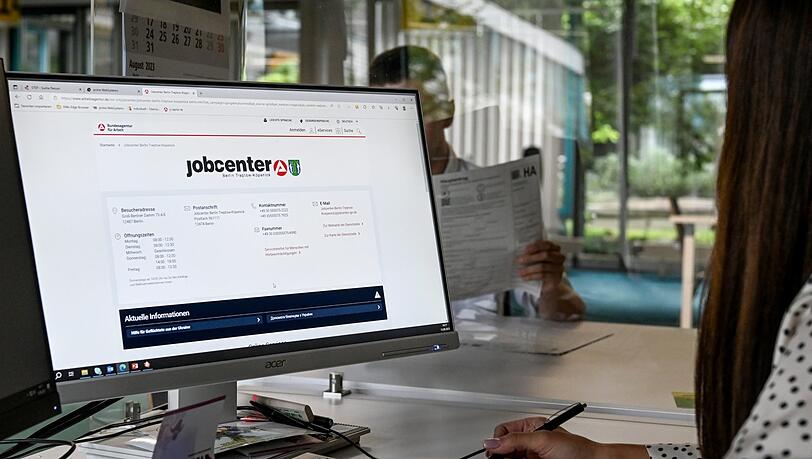 Eine Mitarbeiterin eines Jobcenters sitzt am Computer und spricht mit einem Antragsteller (Symbolbild).