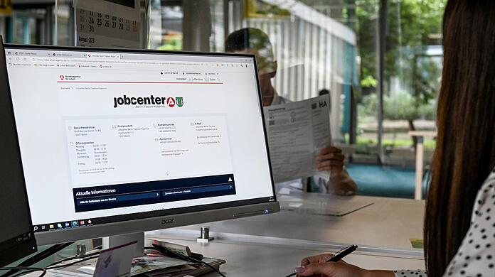 Eine Mitarbeiterin eines Jobcenters sitzt am Computer und spricht mit einem Antragsteller (Symbolbild).