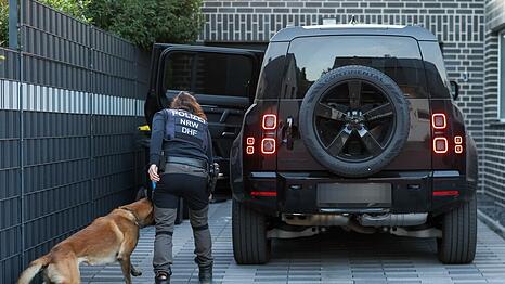 Eine Polizeibeamtin mit ihrem Diensthund durchsucht einen Pkw eines Mannes aus dem Umfeld der Hells Angels.