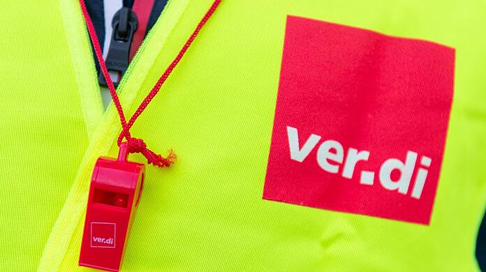 Ein Streikender trägt eine Warnweste mit dem Verdi-Logo (Symbolbild).