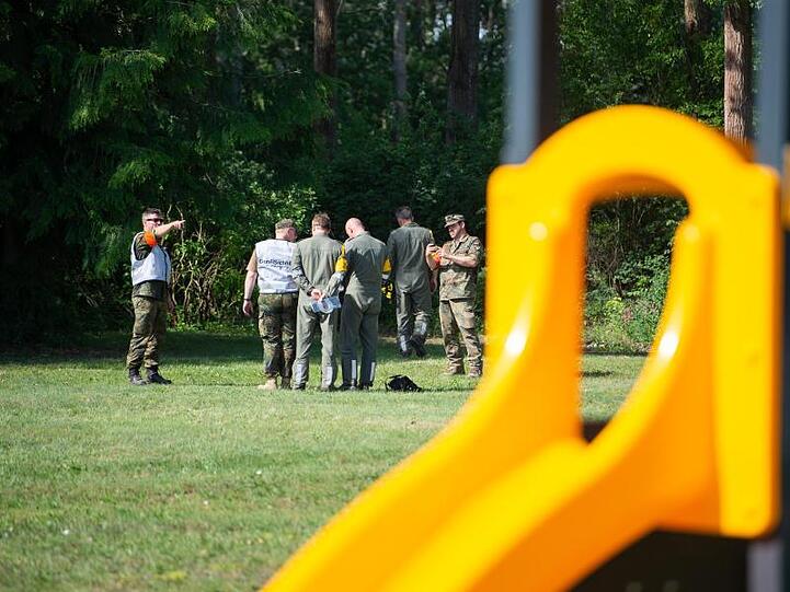 Mitarbeiter der Flugsicherheit der Bundeswehr untersuchen ein Wrackteil auf der Spielwiese eines Kindergartens.