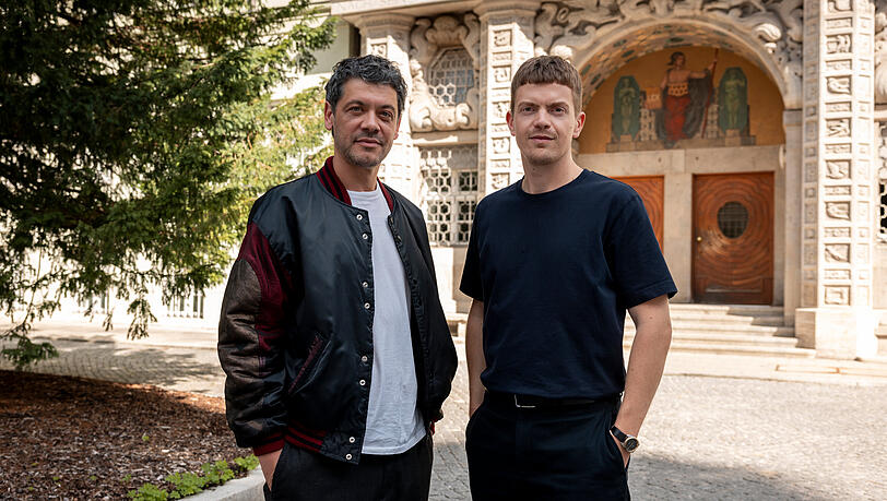 Von links: Carlo Ljubek (Rolle: Nikola Buvak) und Ferdinand Hofer (Rolle: Kalli Hammermann) vor dem Eingang zum Polizeipr&auml;sidium M&uuml;nchen in der Ettstra&szlig;e.