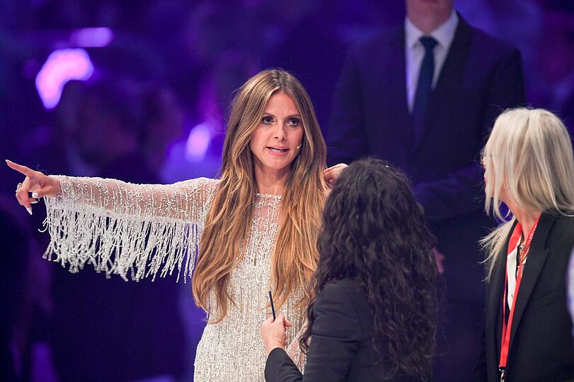 Heidi Klum gibt Anweisungen. Eine TV-Mitarbeiter hält einen Stift in der Hand.