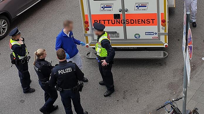 Vier Polizisten stehen hinter einem Rettungsdienst (Symbolbild)