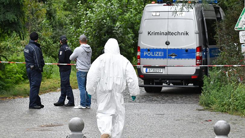 Einsatzkräfte der Polizei und Kriminaltechniker stehen nach dem Fund einer Frauenleiche an einem Weg im Tiergarten. Einsatzkräfte der Polizei und Kriminaltechniker stehen nach dem Fund einer Frauenleiche an einem Weg im Tiergarten.