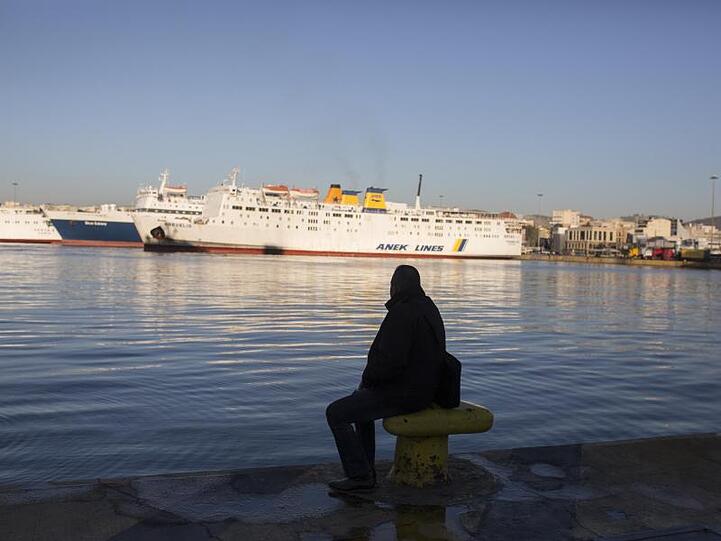 Ein Mann sitzt am Kai im Hafen von Piräus.