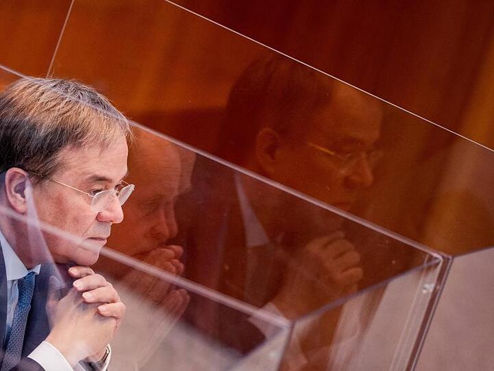 Armin Laschet sitzt in einer Box aus Plexiglas im Plenum des Landtags.