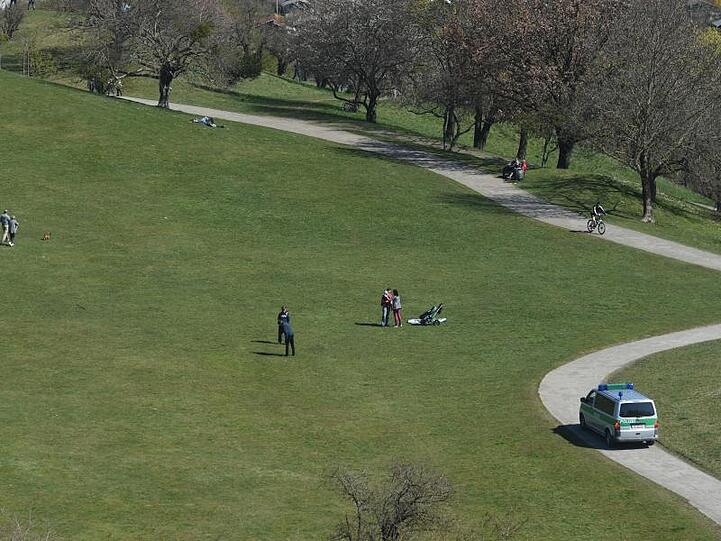 Ein Polizeibus fährt im Olympiapark auf einem Weg durch die Grünflächen auf denen sich Menschen tummeln. Foto: Felix Hörhager/dpa/Archivbild