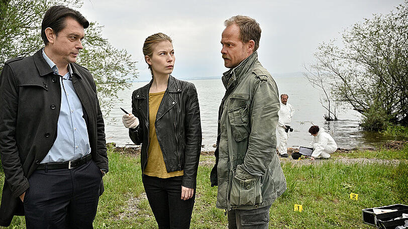 "Die Toten vom Bodensee: Der Blutritt": Ermittler Hanna Zeiler (Nora Waldstätten) und Micha Oberländer (Matthias Koeberlin, r.) erfahren von ihrem Kollegen Thomas Komlatschek (Hary Prinz, l.), dass das Opfer noch lebt und ins Krankenhaus gebracht wird.