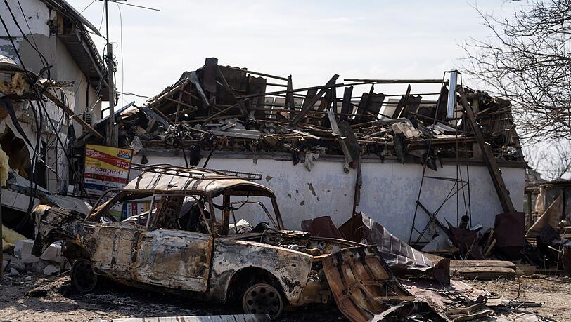 Ein ausgebranntes Auto steht in Mykolaiw vor beschädigten Häusern nach einem russischen Bombenangriff.