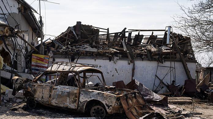 Ein ausgebranntes Auto steht in Mykolaiw vor beschädigten Häusern nach einem russischen Bombenangriff.