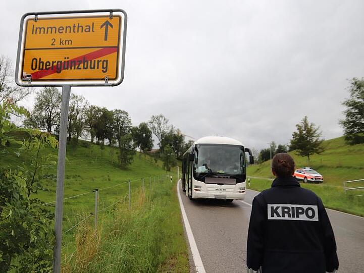 Eine Mitarbeiterin der Kripo geht auf den am Straßenrand stehenden Linienbus zu.