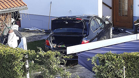 Der BMW fuhr durch einen Zaun und eine Hecke und kam erst an einer Hauswand zum Stehen.