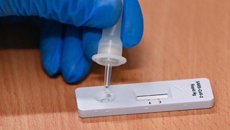 Eine Mitarbeiterin vom Gesundheitsamt tropft eine Flüssigkeit auf einen Corona-Schnelltest.