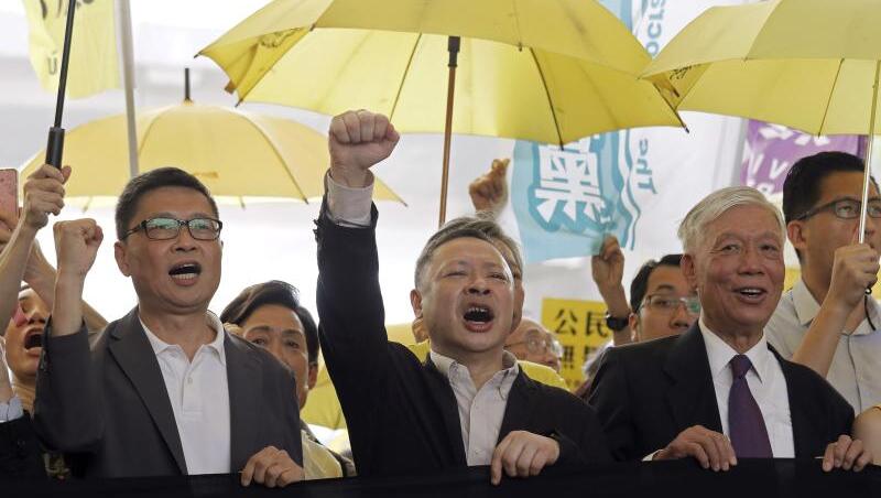 Die Anführer der "Regenschirm-Bewegung", Chan Kin Man (l-r), Benny Tai und Chu Yiu Ming rufen Parolen, bevor sie ins Gericht gehen. Die Anführer der "Regenschirm-Bewegung", Chan Kin Man (l-r), Benny Tai und Chu Yiu Ming rufen Parolen, bevor sie ins Gericht gehen.