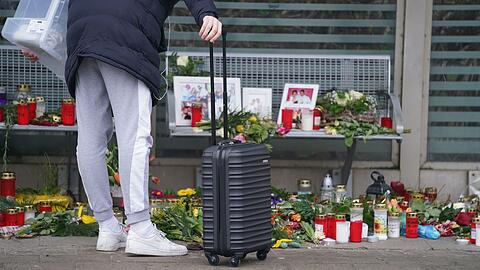 Eine Reisende schaut sich die Blumen, Kerzen und verschiedene Bilder im Wartehäuschen am Bahnhof zum Gedenken an die Opfer der Messerattacke an.