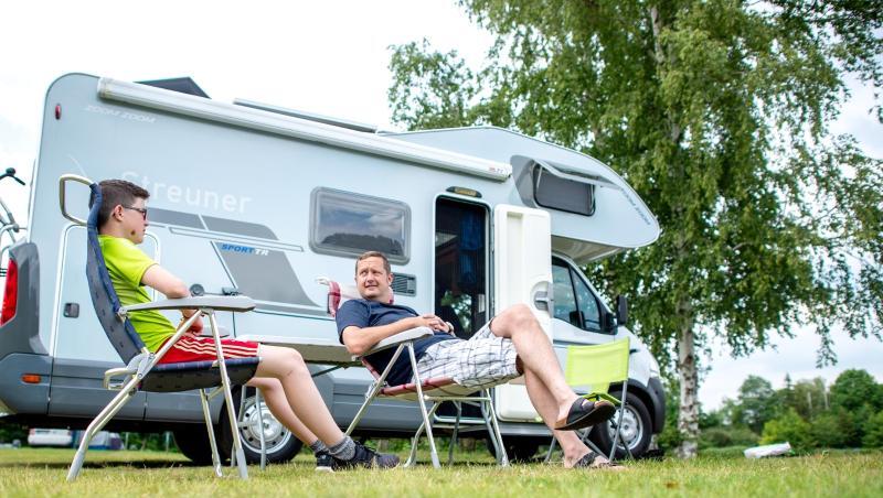 Ein Mann und ein Kind sitzen vor ihrem Wohnmobil. Foto: Hauke-Christian Dittrich/dpa/Symbolbild Ein Mann und ein Kind sitzen vor ihrem Wohnmobil. Foto: Hauke-Christian Dittrich/dpa/Symbolbild
