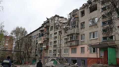 Menschen betrachten ein beschädigtes Gebäude nach einem Raketenangriff in der Stadt Slowjansk.