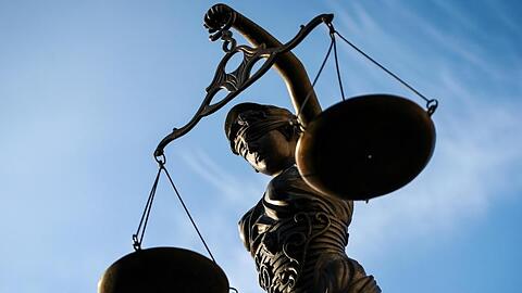 Eine Statue der Justitia hält eine Waage in der Hand.