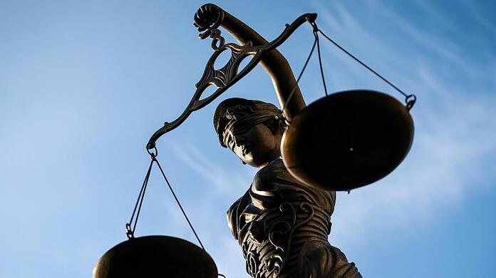 Eine Statue der Justitia hält eine Waage in der Hand.