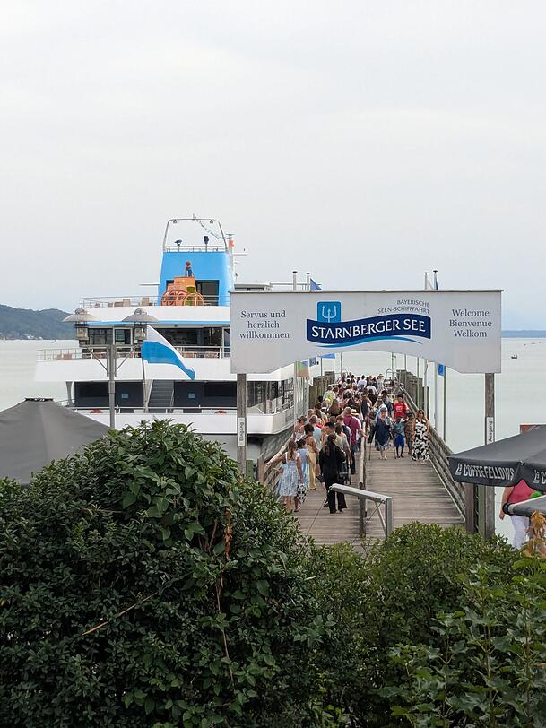 Menschen str&ouml;men am Starnberger See auf eines der Ausflugsschiffe.