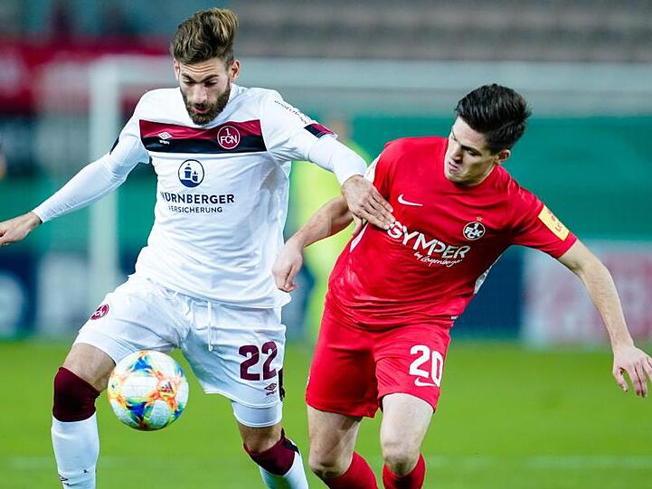 Nürnbergs Enrico Valentini und Kaiserslauterns Dominik Schad (l-r.) kämpfen um den Ball. Foto: Uwe Anspach/dpa