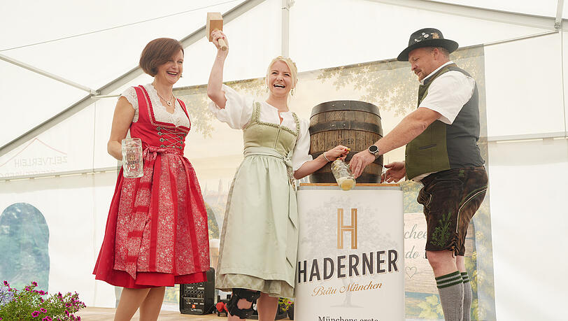 Die Bierk&ouml;nigin Katharina Kastenm&uuml;ller (Mitte) zapft das erste Fass Jubil&auml;umsbier mit Marta und Thomas Girg.