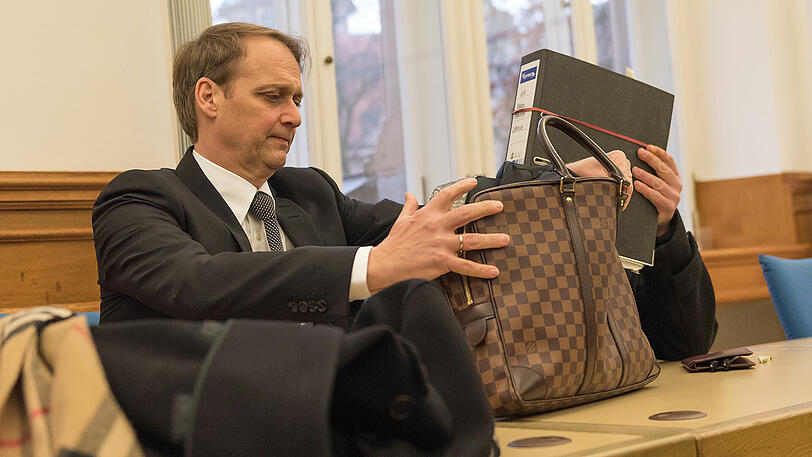 Der Angeklagte versteckt sich hinter einem Aktenordner.